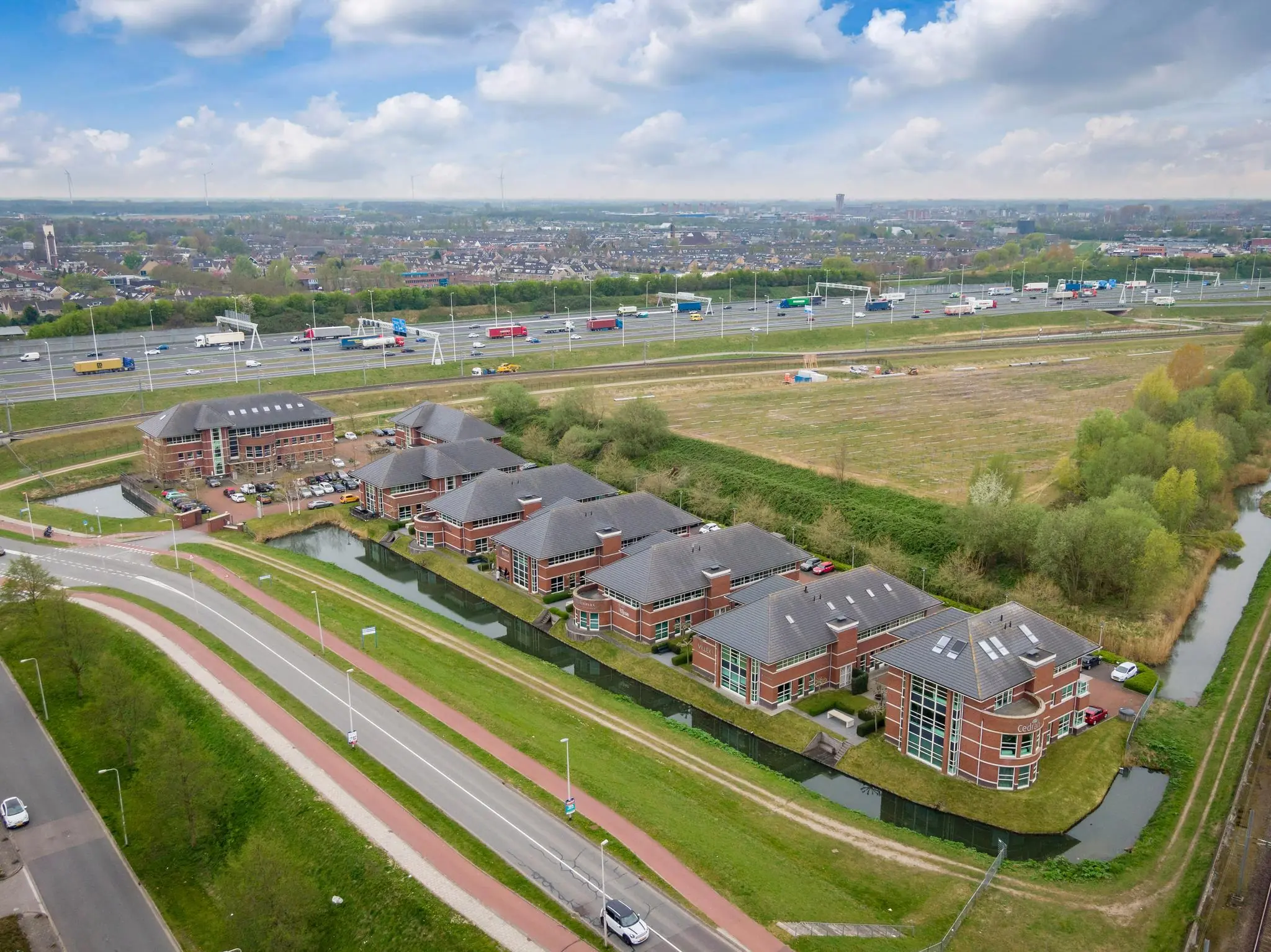 Luchtfoto van kantoorpanden aan de 1e Barendrechtseweg nabij snelweg A29 met woonwijk op de achtergrond.